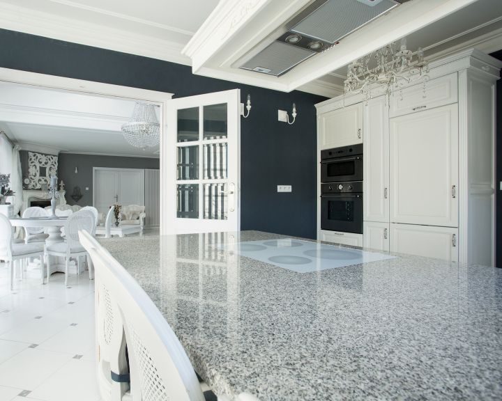 a kitchen with a marble counter top and white cabinets.