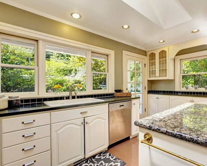 a kitchen with marble counter tops and white cabinets.