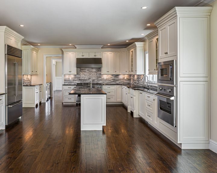 a large kitchen with white cabinets and wood floors.